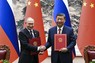 共同声明に署名した後、握手を交わすロシアのプーチン大統領（左）と中国の習近平国家主席＝北京の人民大会堂で16日、新華社AP