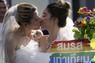 タイ・バンコクで開かれたパレードで同性婚を支持するポスターを持ちながらキスをする女性ら＝2023年6月、AP共同