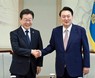 韓国大統領府で開かれた会談で握手する尹錫悦大統領（右）と野党「共に民主党」の李在明代表＝ソウルで29日、聯合・共同